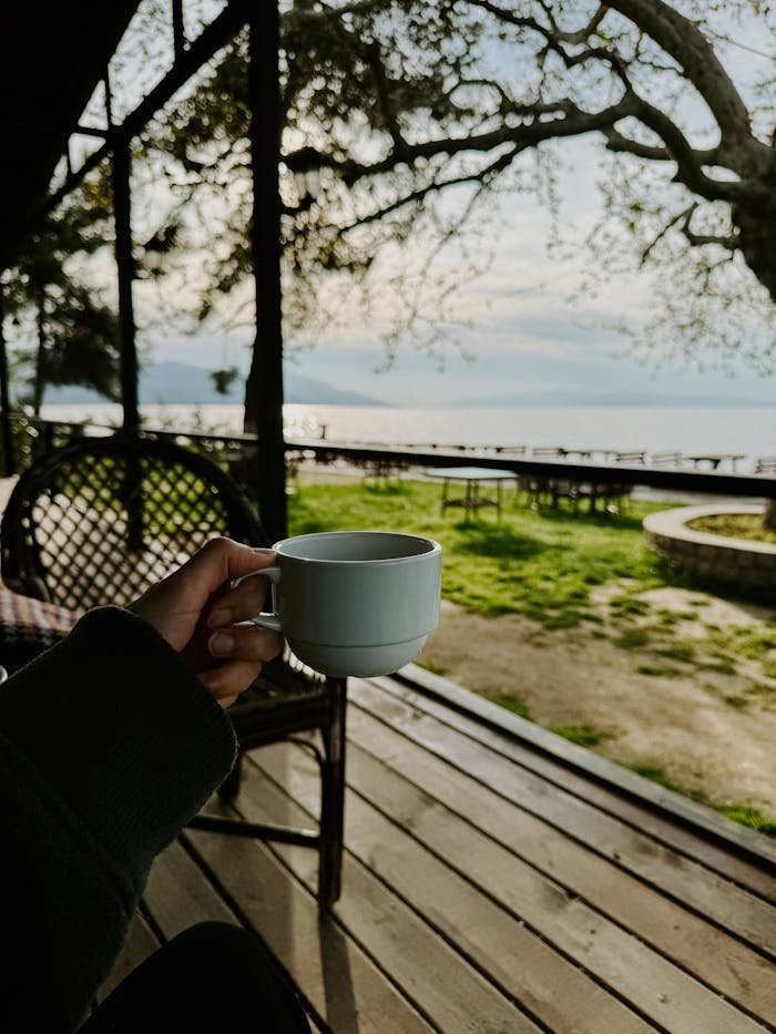 Enjoying a peaceful moment with coffee, overlooking the sea from a wooden deck.